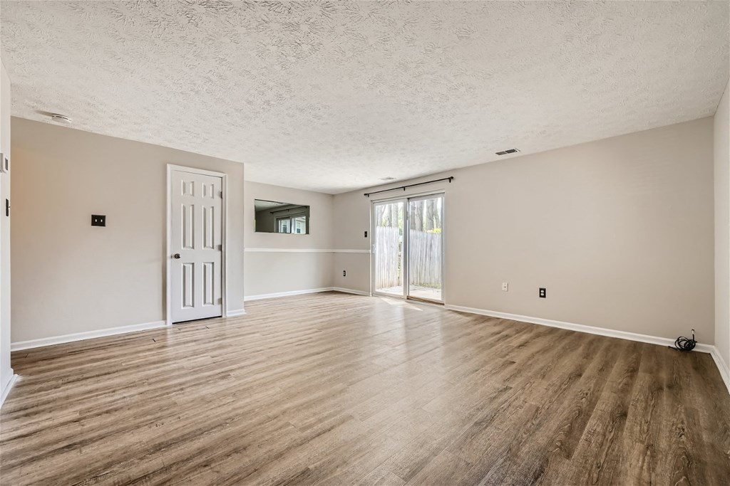 the living room and dining room of an empty house with wood floors