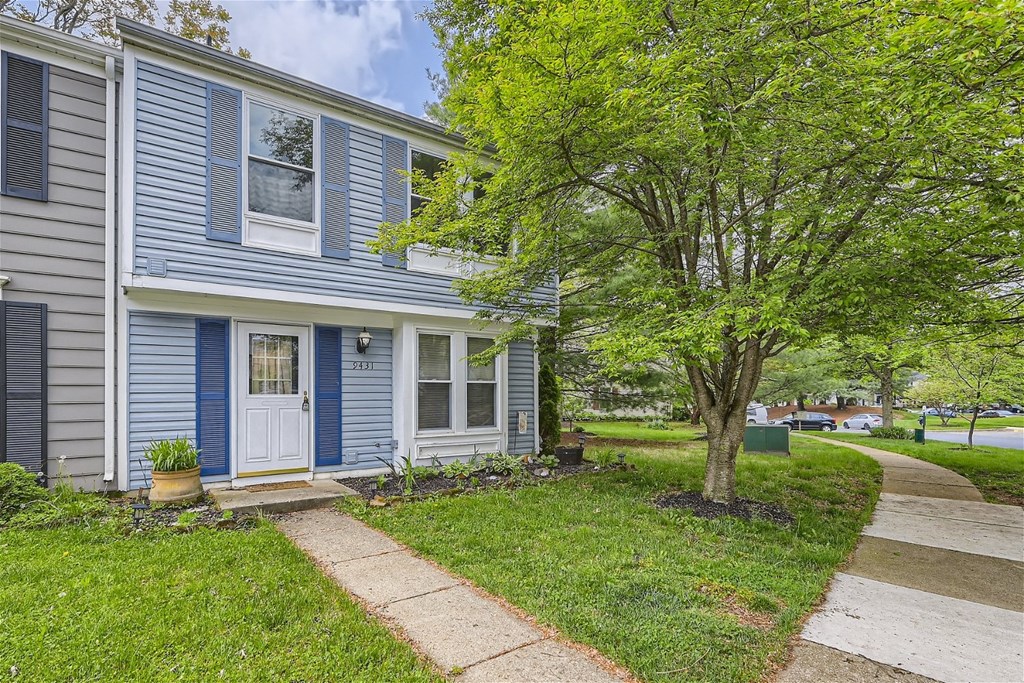a blue house with a sidewalk and trees in front of it