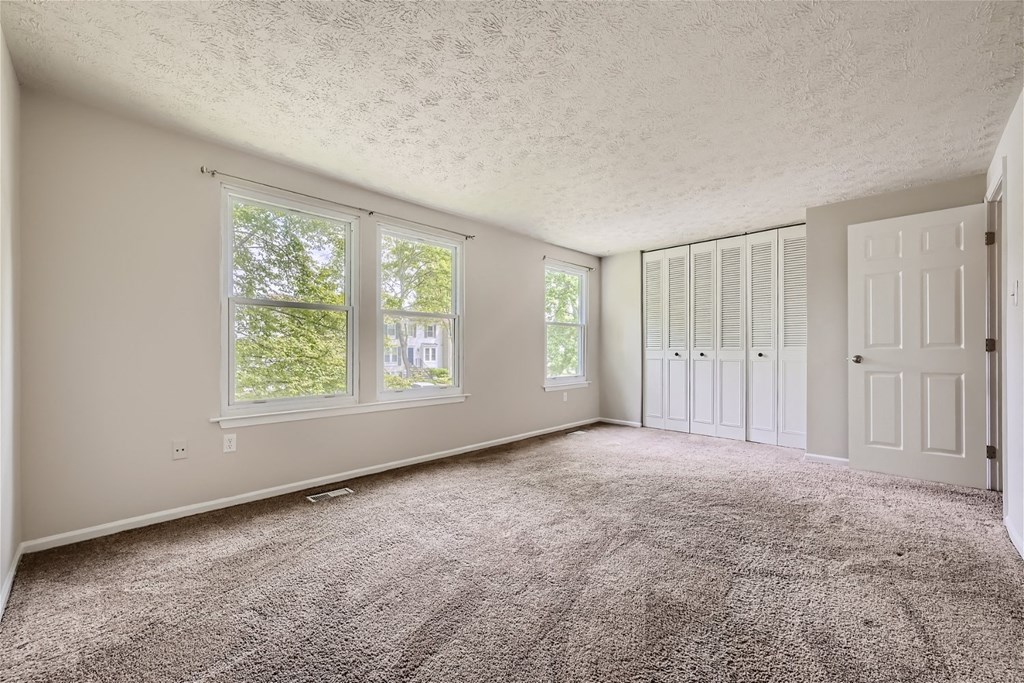 an empty living room with carpet and white doors