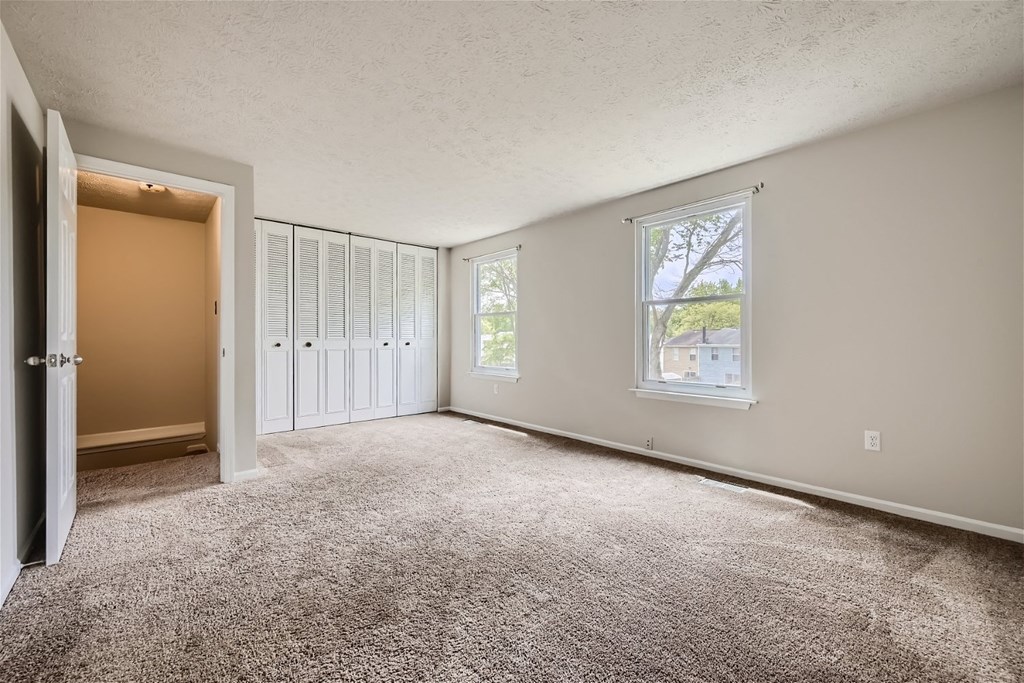 an empty living room with carpet and a door to a closet