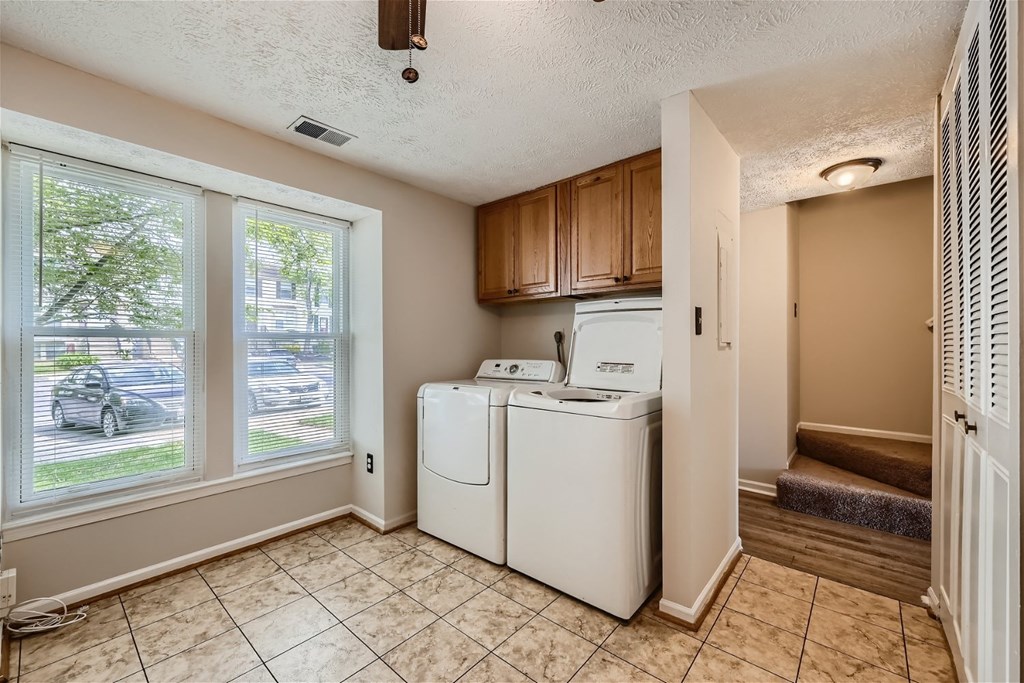 a laundry room with a washer and dryer in it and two large windows