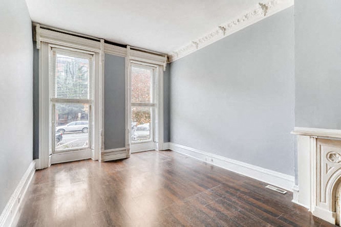 an empty living room with wood floors and a fireplace