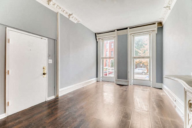 an empty living room with wood floors and a door