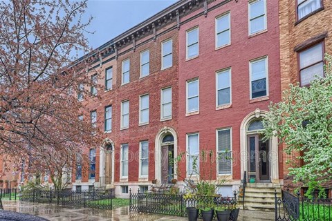 A red brick building with a black fence in front.
