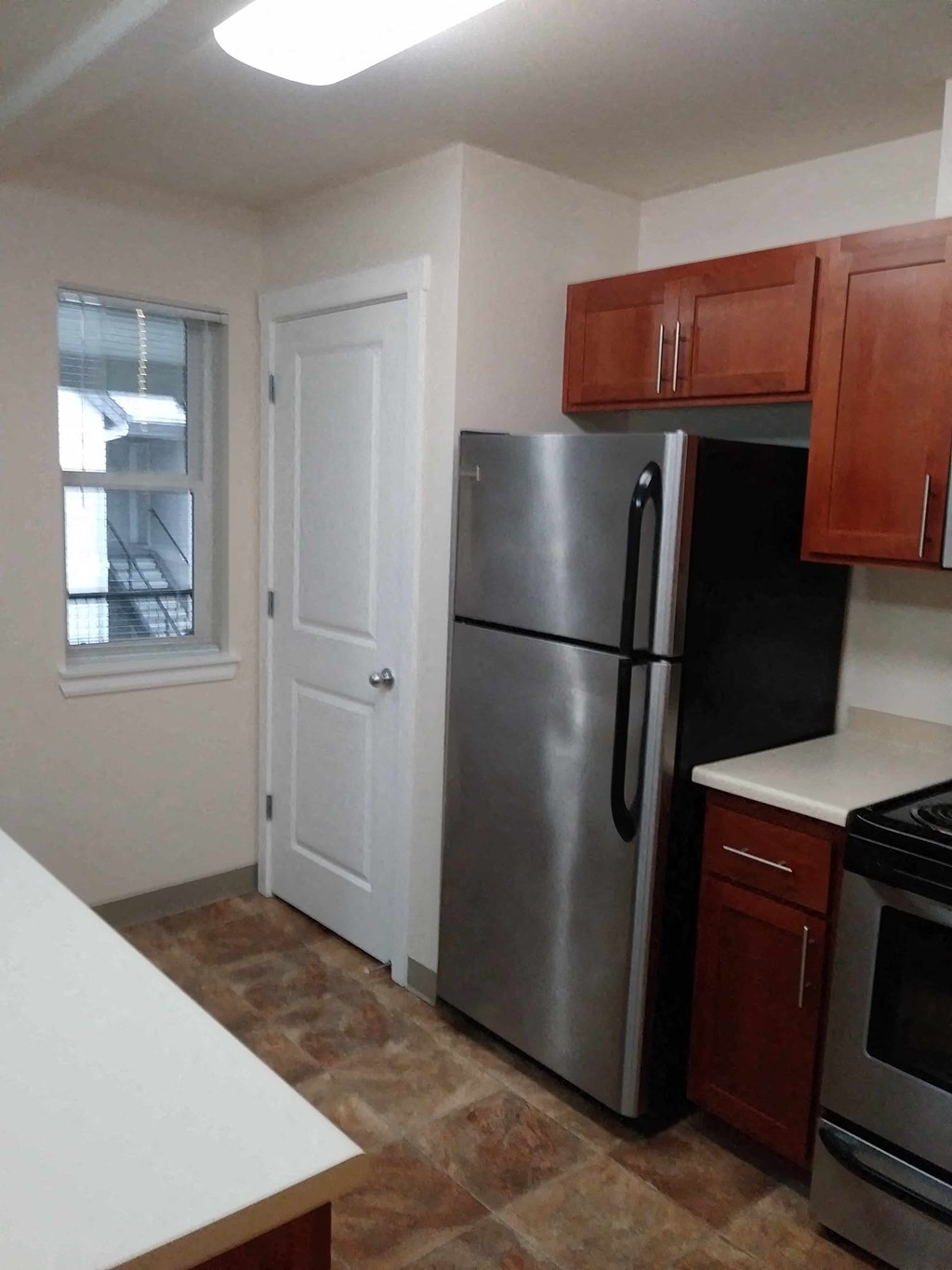 a kitchen with a stainless steel refrigerator and a window