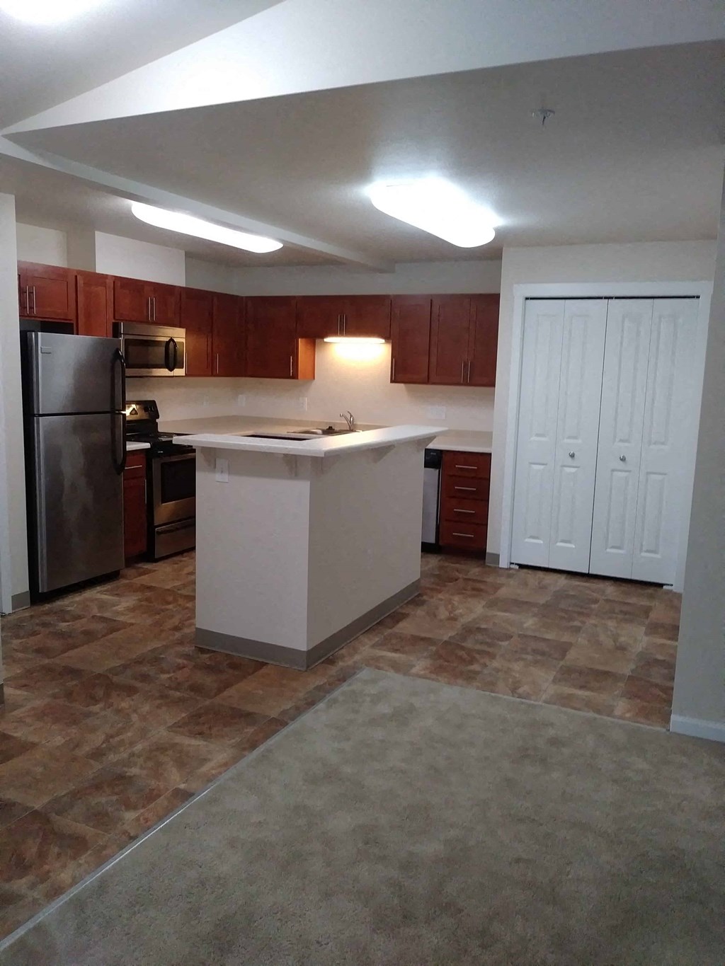 an empty kitchen with an island and a refrigerator