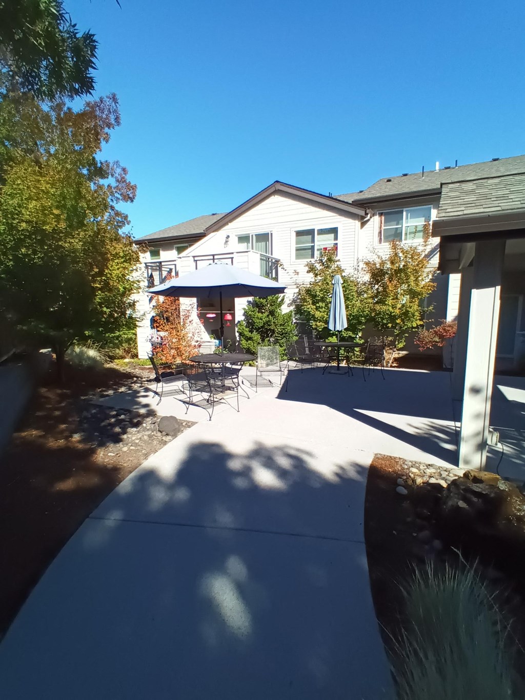 a patio with chairs and umbrellas in front of a house