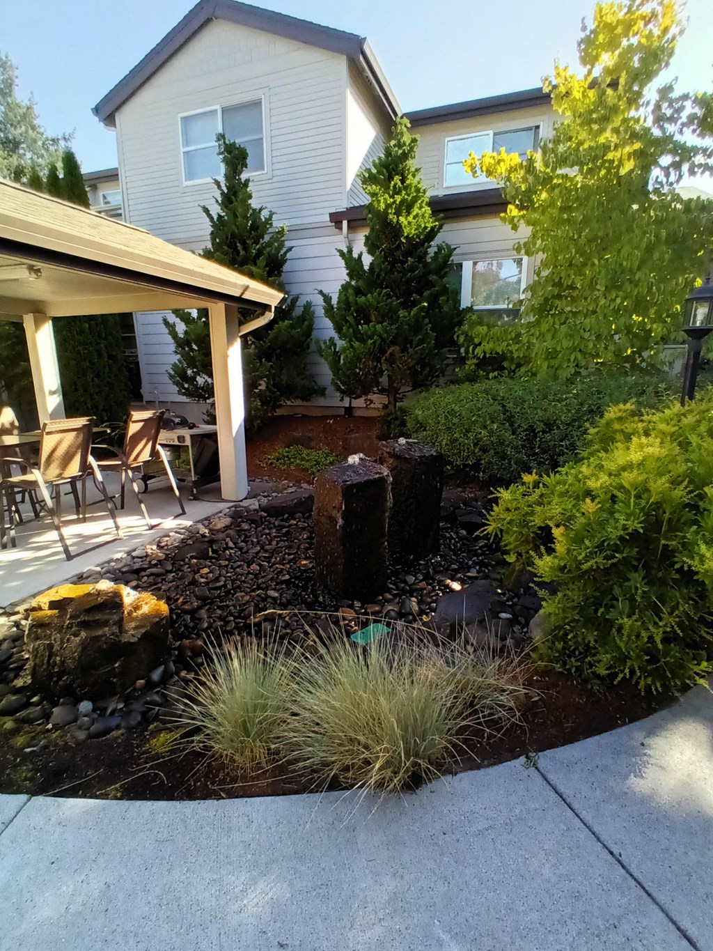 a front yard with a garden and a house with a patio