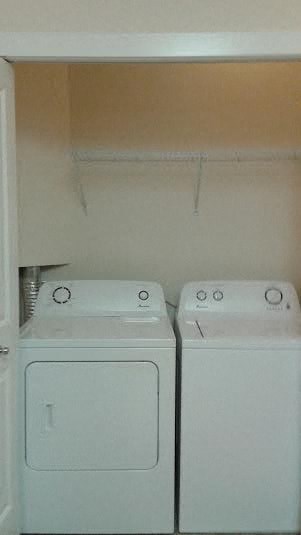 two washer and dryers in a white closet
