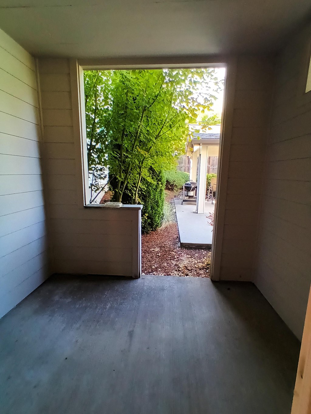 a view from the inside of a small room looking out into a yard with trees