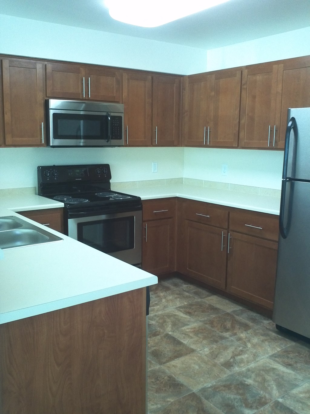 an empty kitchen with wooden cabinets and stainless steel appliances
