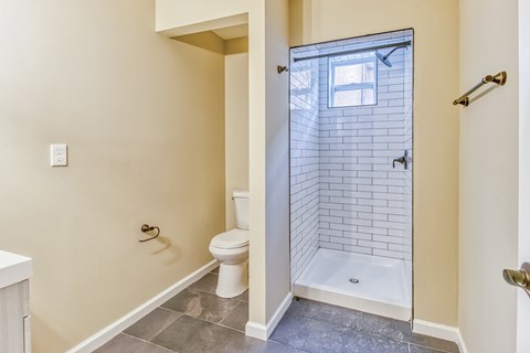A white toilet sits in a bathroom with a walk-in shower.
