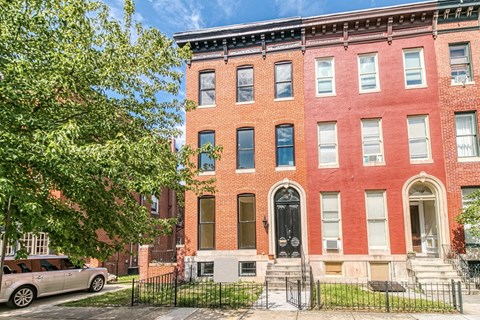 A red brick building with a black gate in front.
