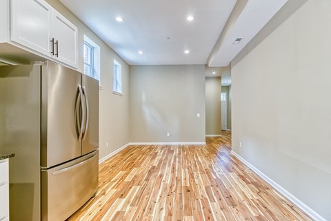A kitchen with a stainless steel refrigerator and wooden flooring.