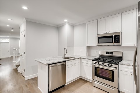 A modern kitchen with white cabinets and stainless steel appliances.