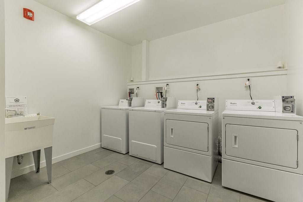 a row of washing machines and dryers in a laundry room