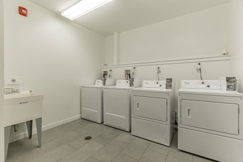 a row of washing machines and dryers in a laundry room