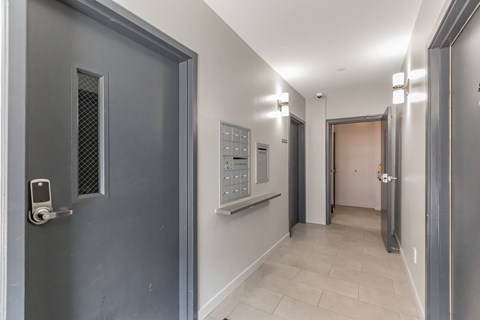 A hallway with a grey door on the left and a white door on the right.