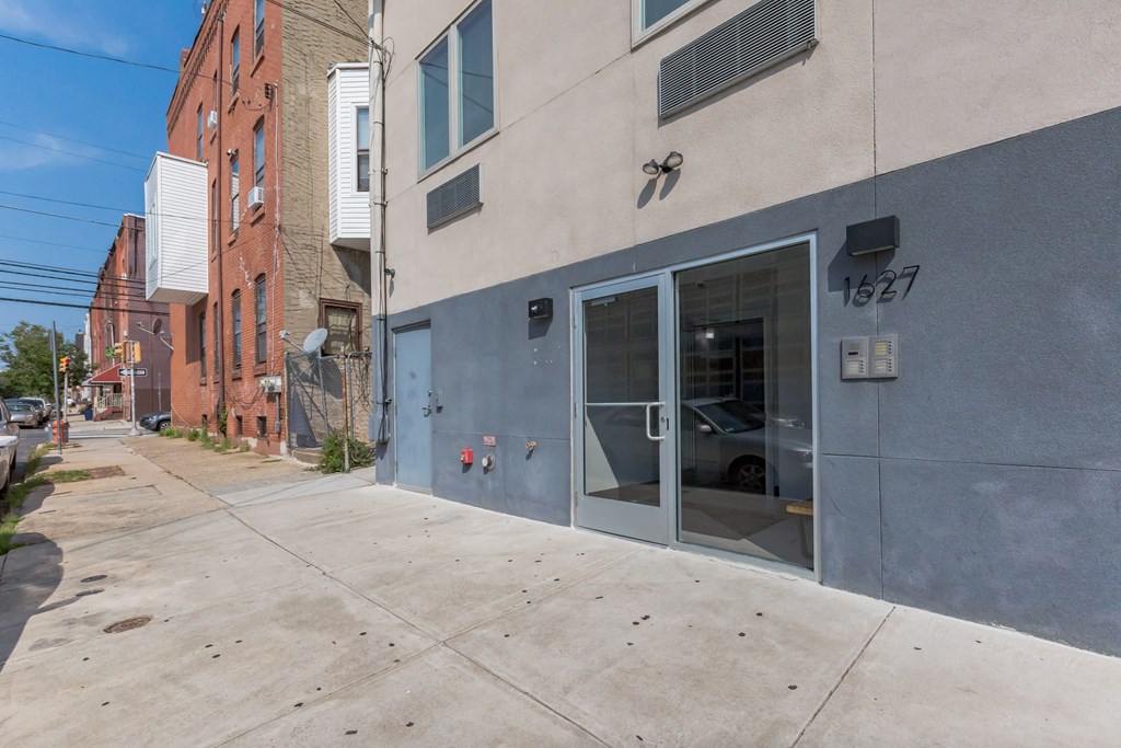 the side of a building with a door and a sidewalk
