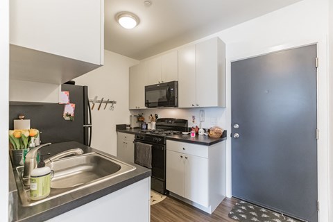 a kitchen with white cabinets and black appliances and a stainless steel sink