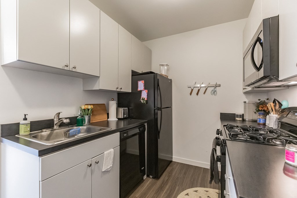 an apartment kitchen with stainless steel appliances and a black refrigerator
