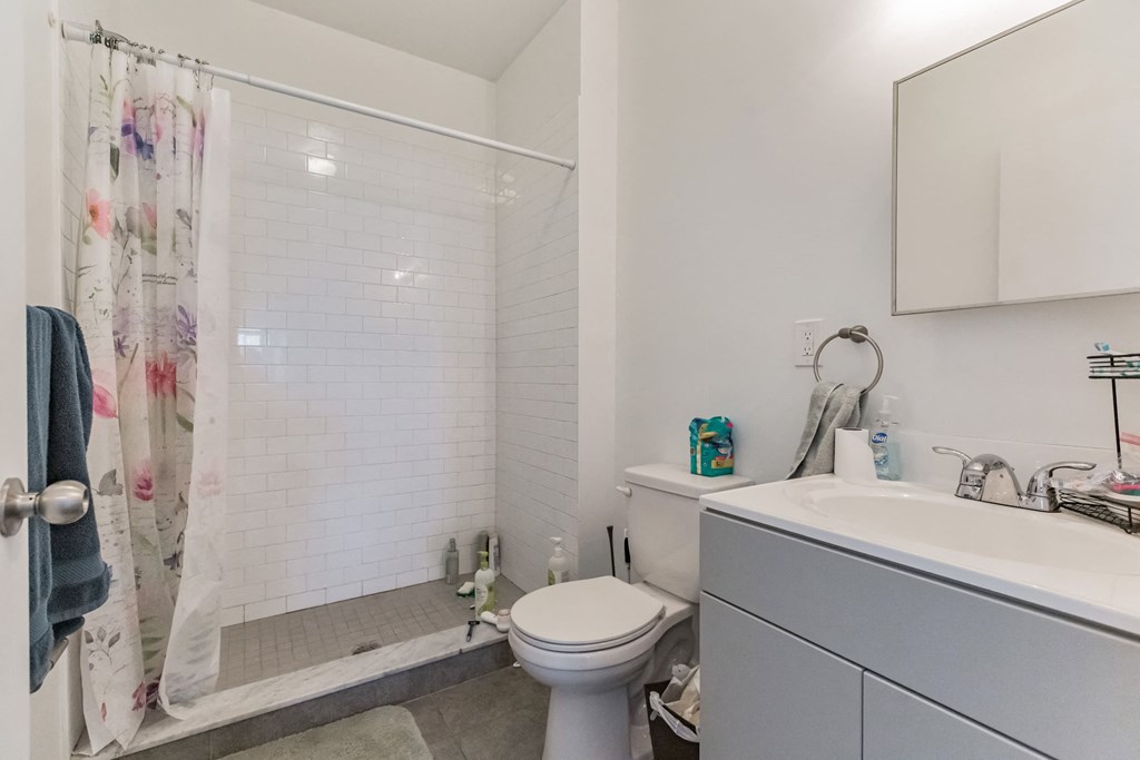 a white bathroom with a shower and a toilet and a sink