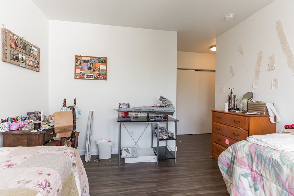 a bedroom with two beds and a desk and a dresser