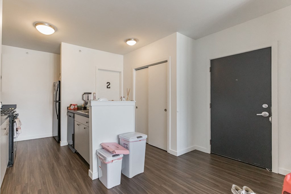 a living room with a kitchen and a black door
