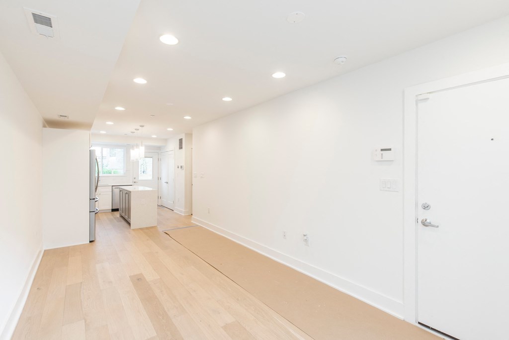 a long hallway with white walls and wood floors
