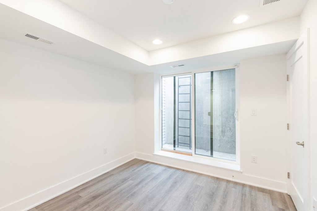 an empty living room with a large window and wood flooring
