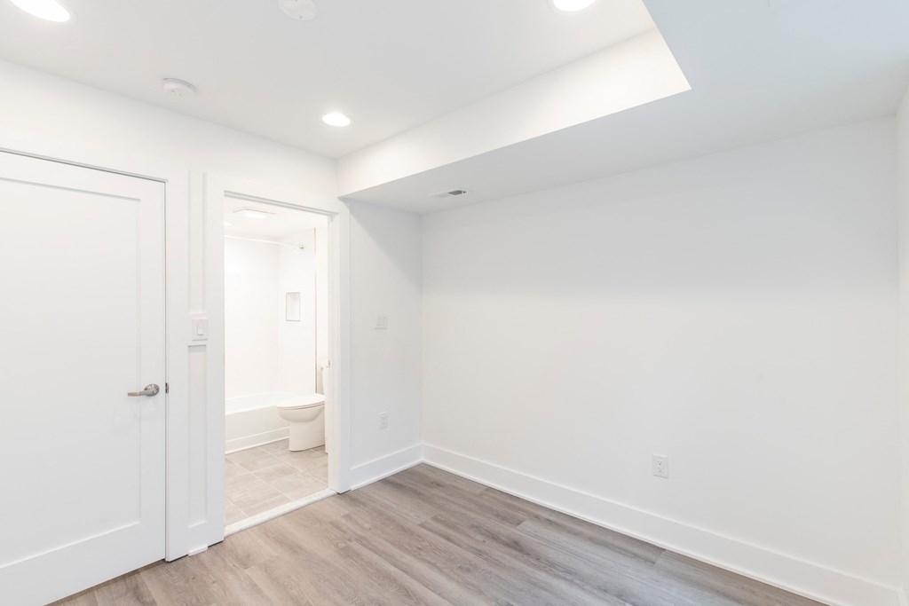 a living room with white walls and a door to a bathroom