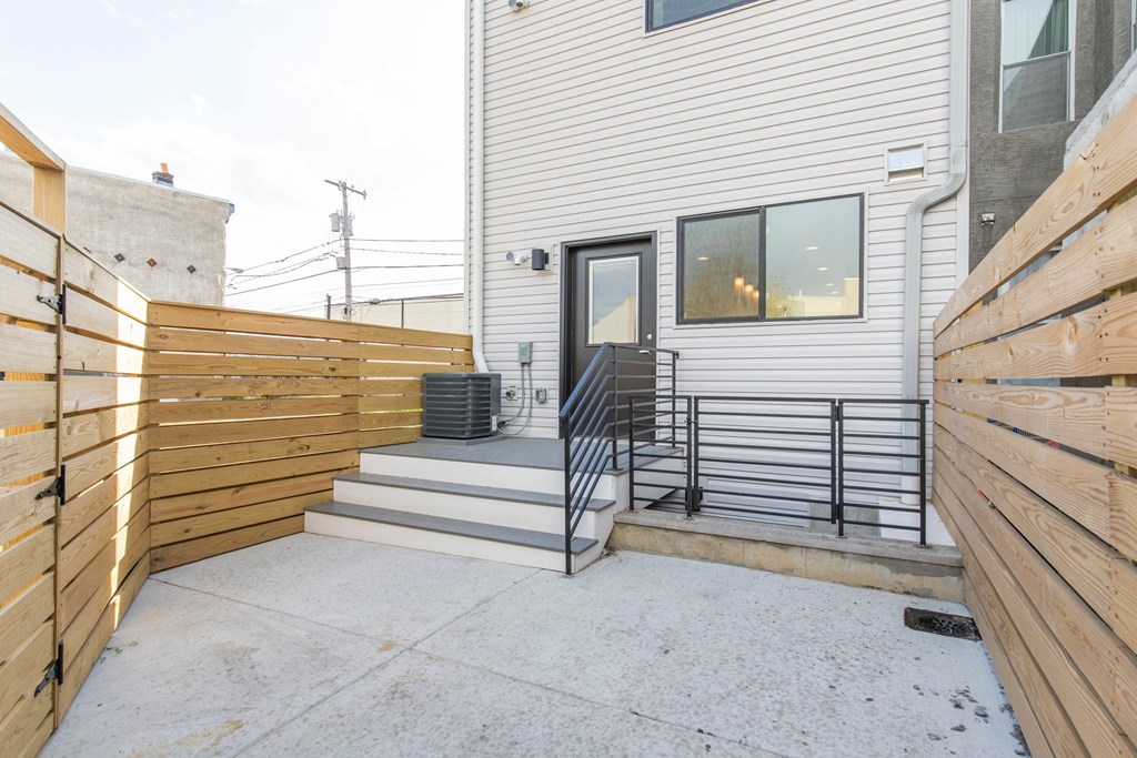 the back of a white house with a patio and a wooden fence