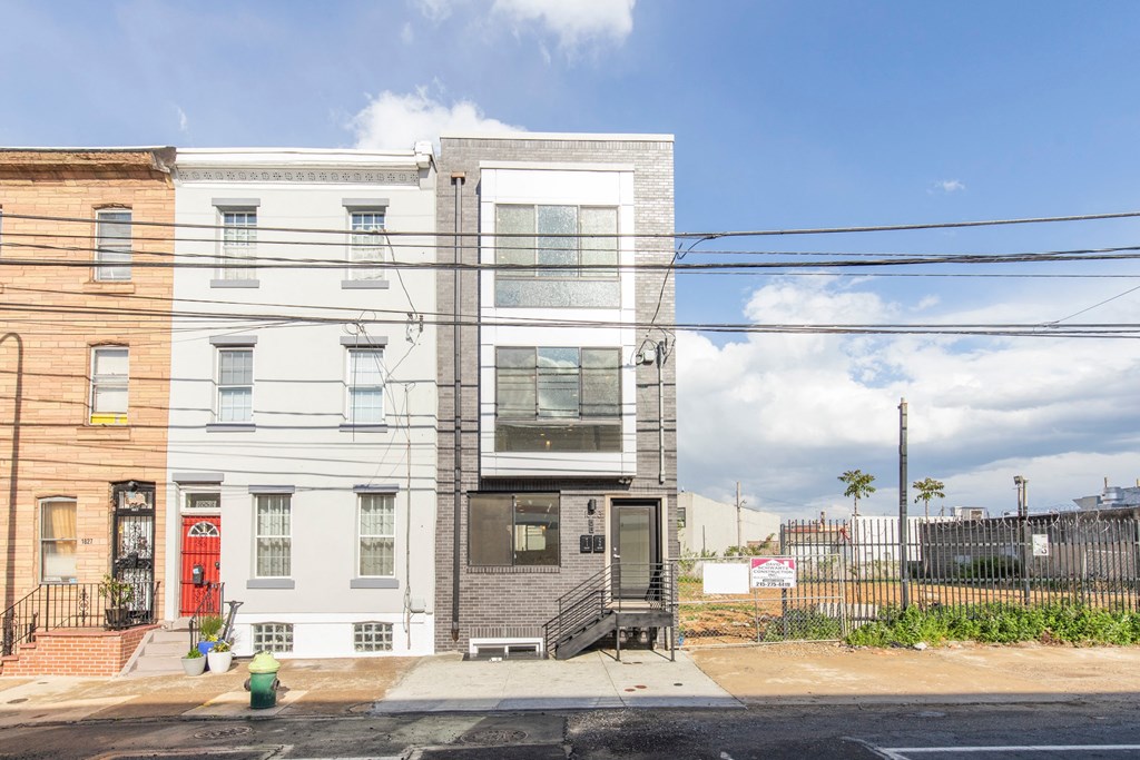 the front of a white and gray house with a red door