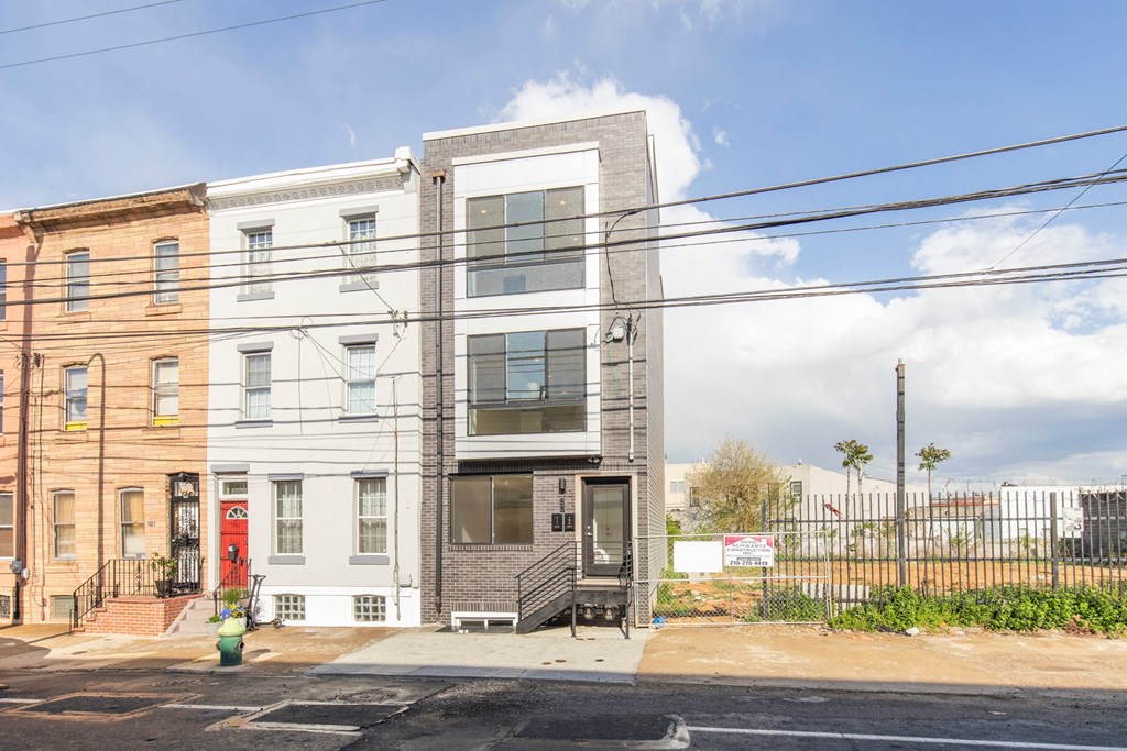 the exterior of a building with a gray facade and a red door