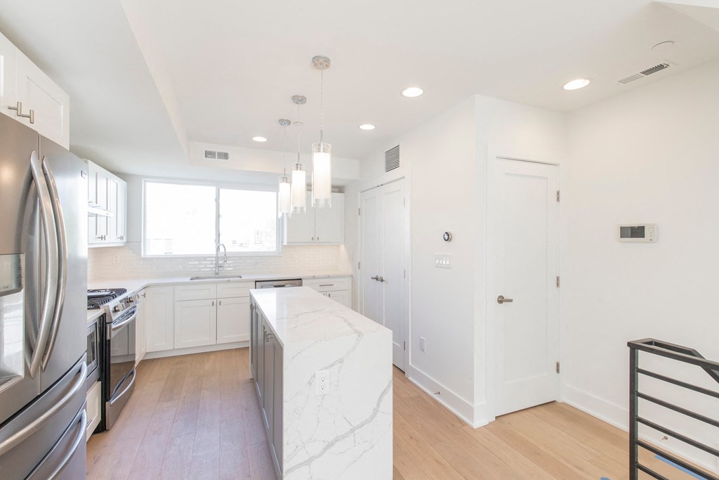 a kitchen with white cabinets and a marble counter top