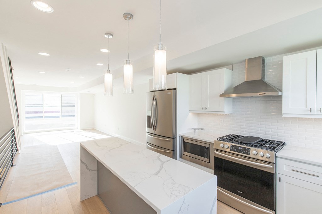 a white kitchen with stainless steel appliances and white counter tops