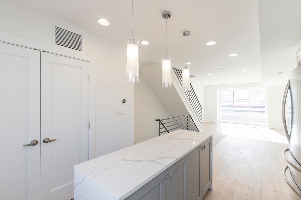 a white kitchen with a marble counter top and a staircase