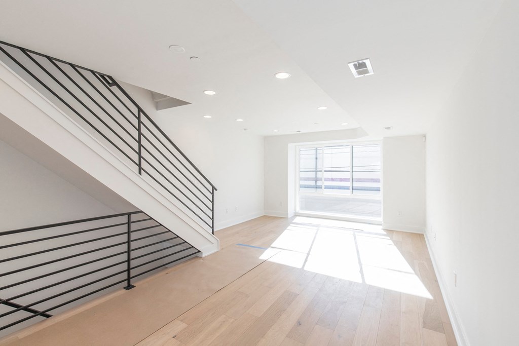 a large white room with a staircase and a glass door