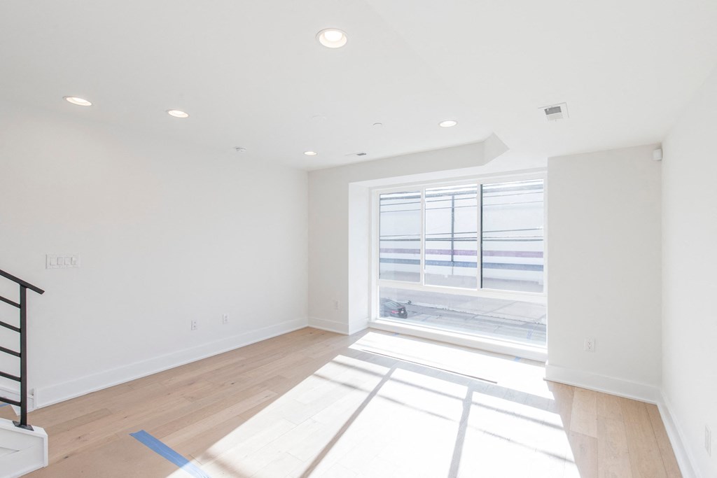 an empty living room with a large window and white walls