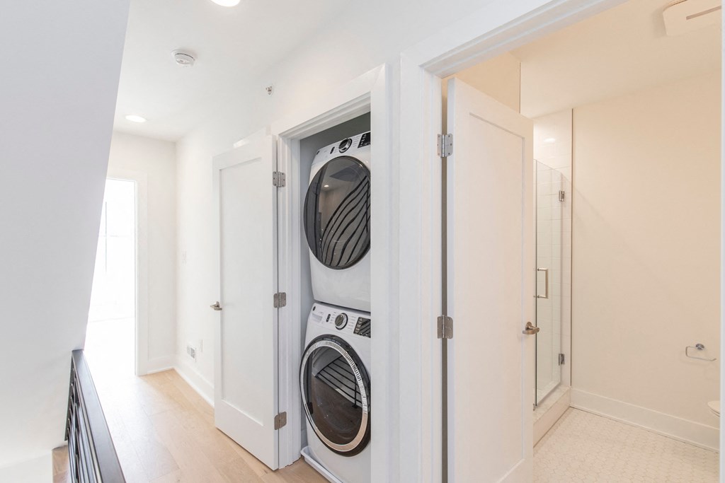 a front loading washer and dryer in a white laundry room with a door