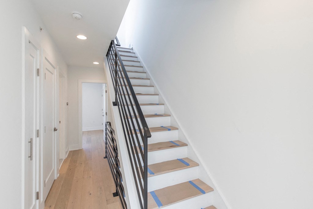 a staircase in a home with white walls and wood floors