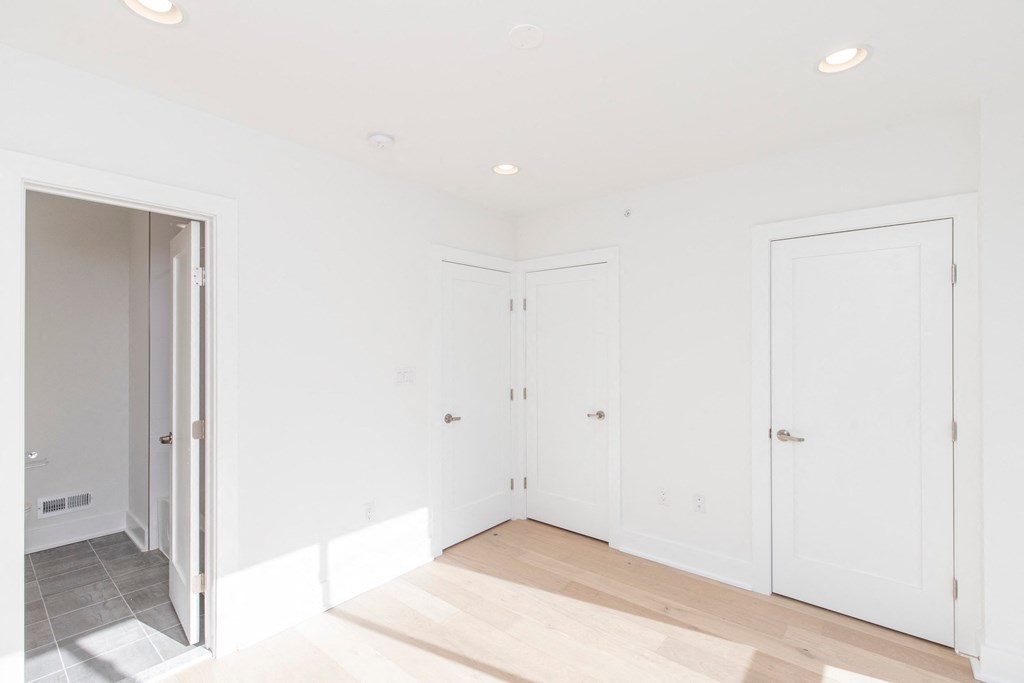 a bedroom with white walls and white doors and a wood floor