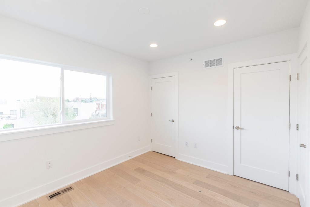 a bedroom with white walls and a window and a door