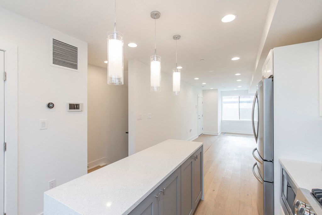 a kitchen with a white counter top and a stainless steel refrigerator