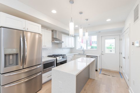 a white kitchen with stainless steel appliances and white counter tops