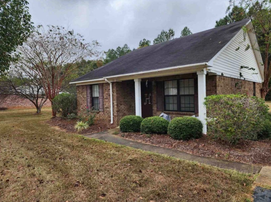 A small house with a white front porch and a black roof.