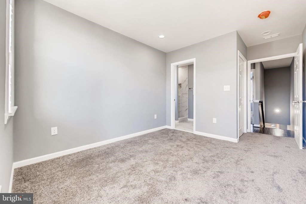 a bedroom with a carpeted floor and a door to a bathroom