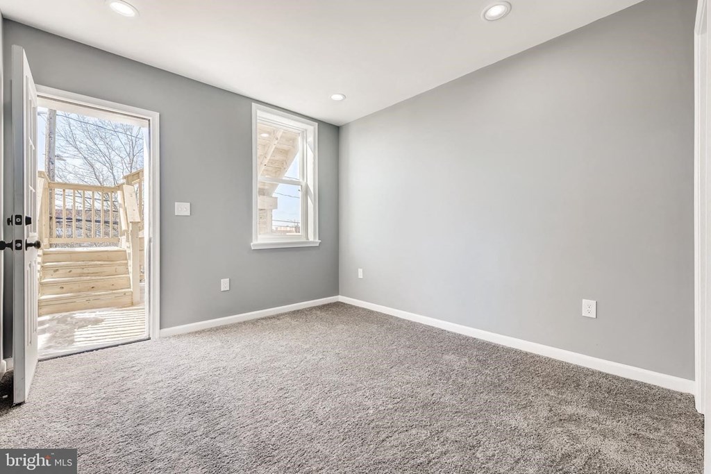 an empty living room with gray walls and a door to a patio