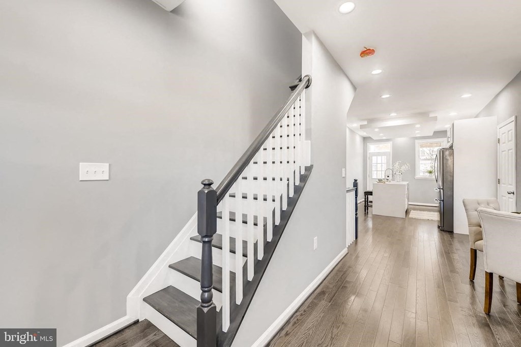 a white staircase with black railings leading up to a living room