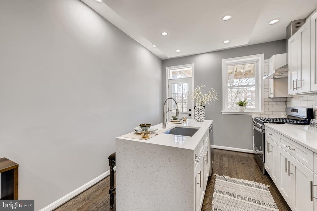 a white kitchen with a white counter top and a sink